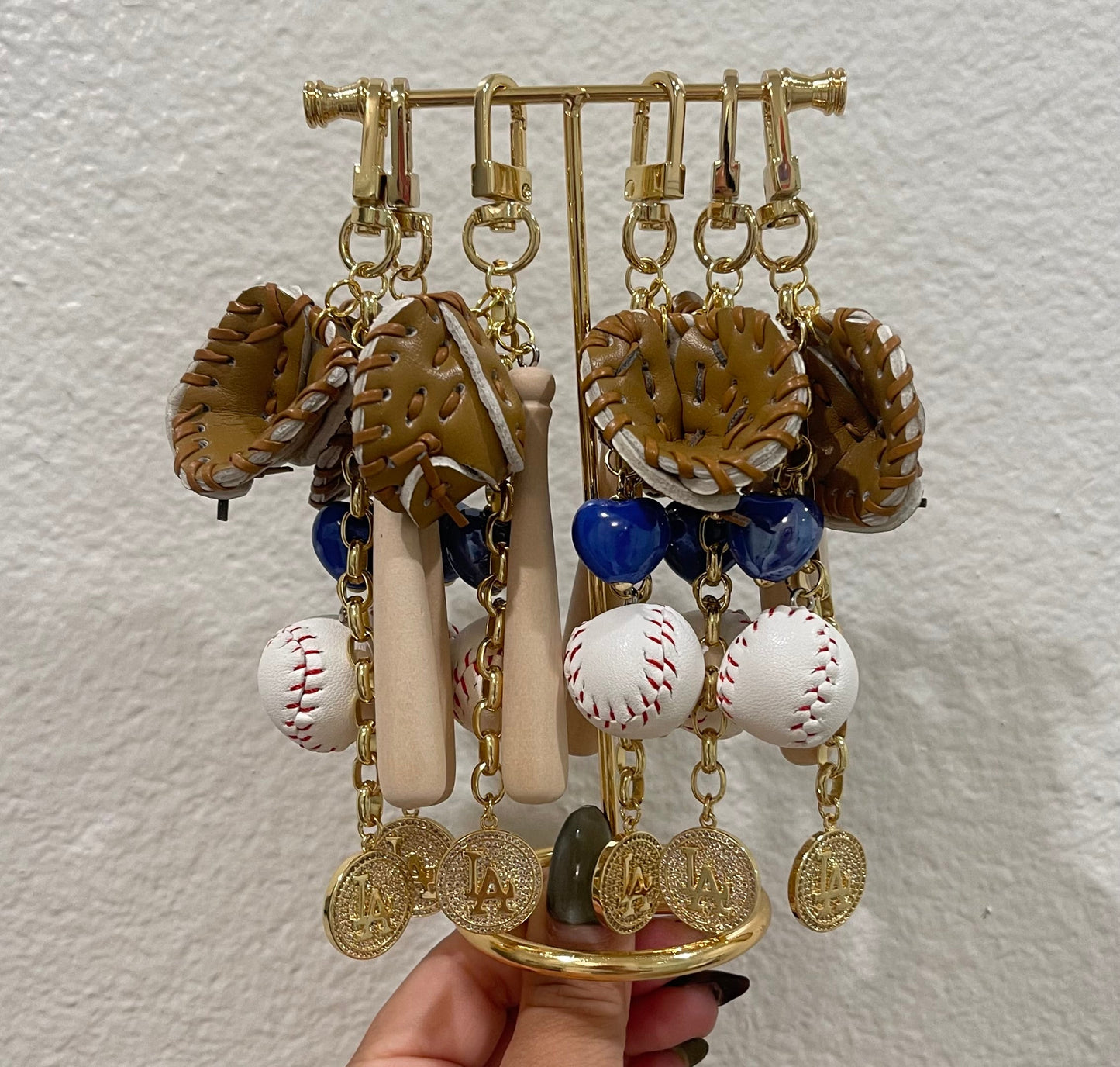 Hand holding a decorative keychain with various charms against a plain background