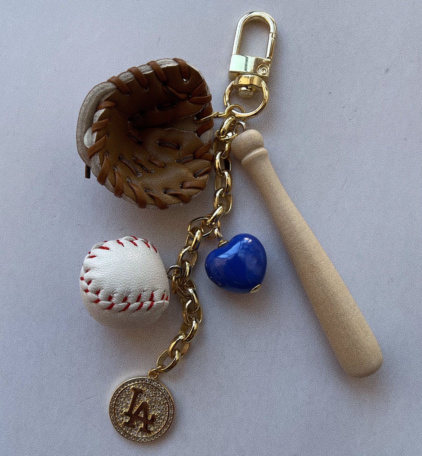 Keychain with baseball, bat, and heart charm on a light gray background